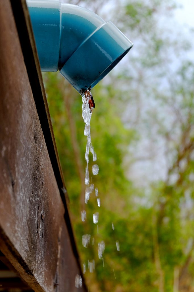 Water pouring from a rain gutter downspouts and yard drainage